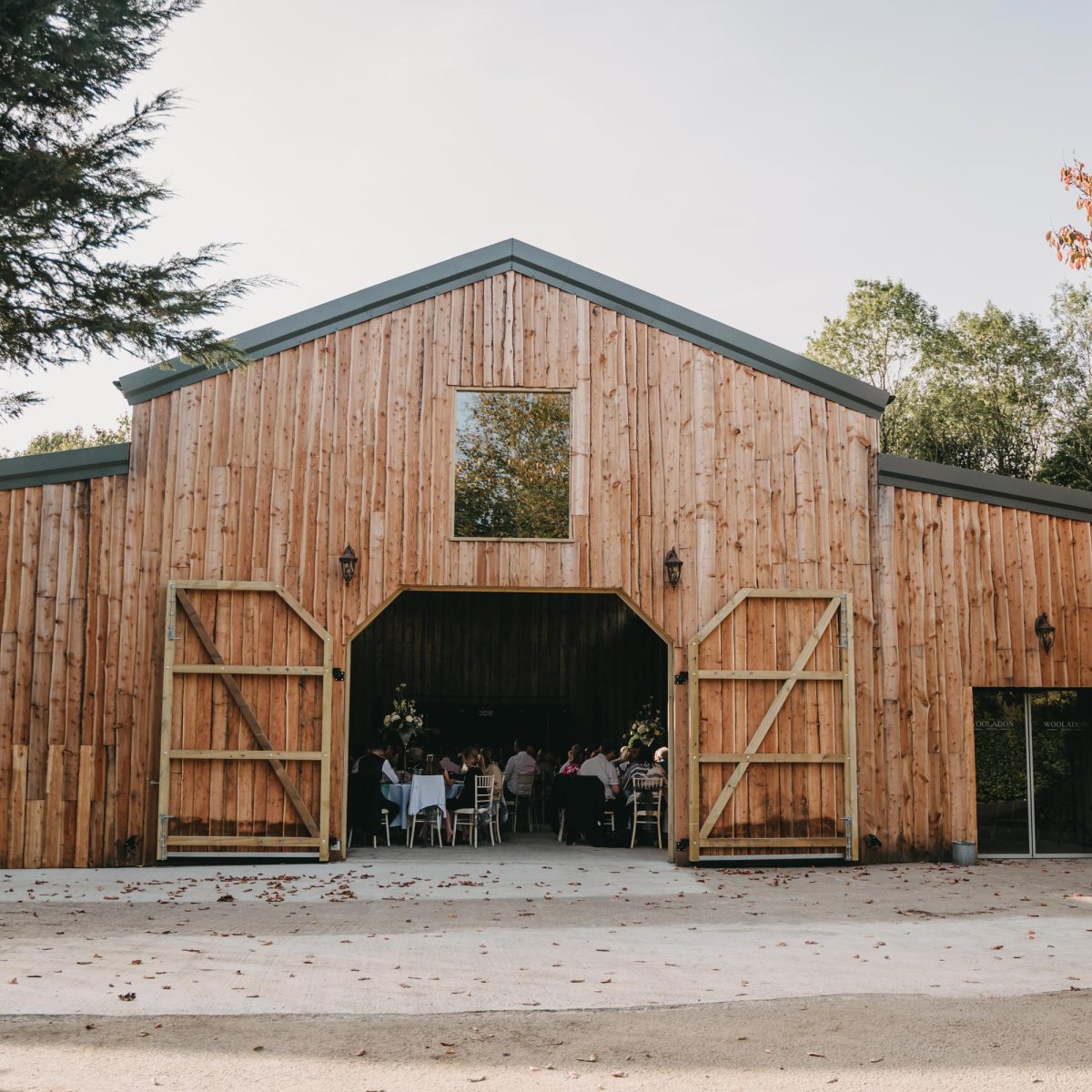 The outside of the barn at Wooladon Estate with the doors open showing the guests sitting inside for a wedding reception