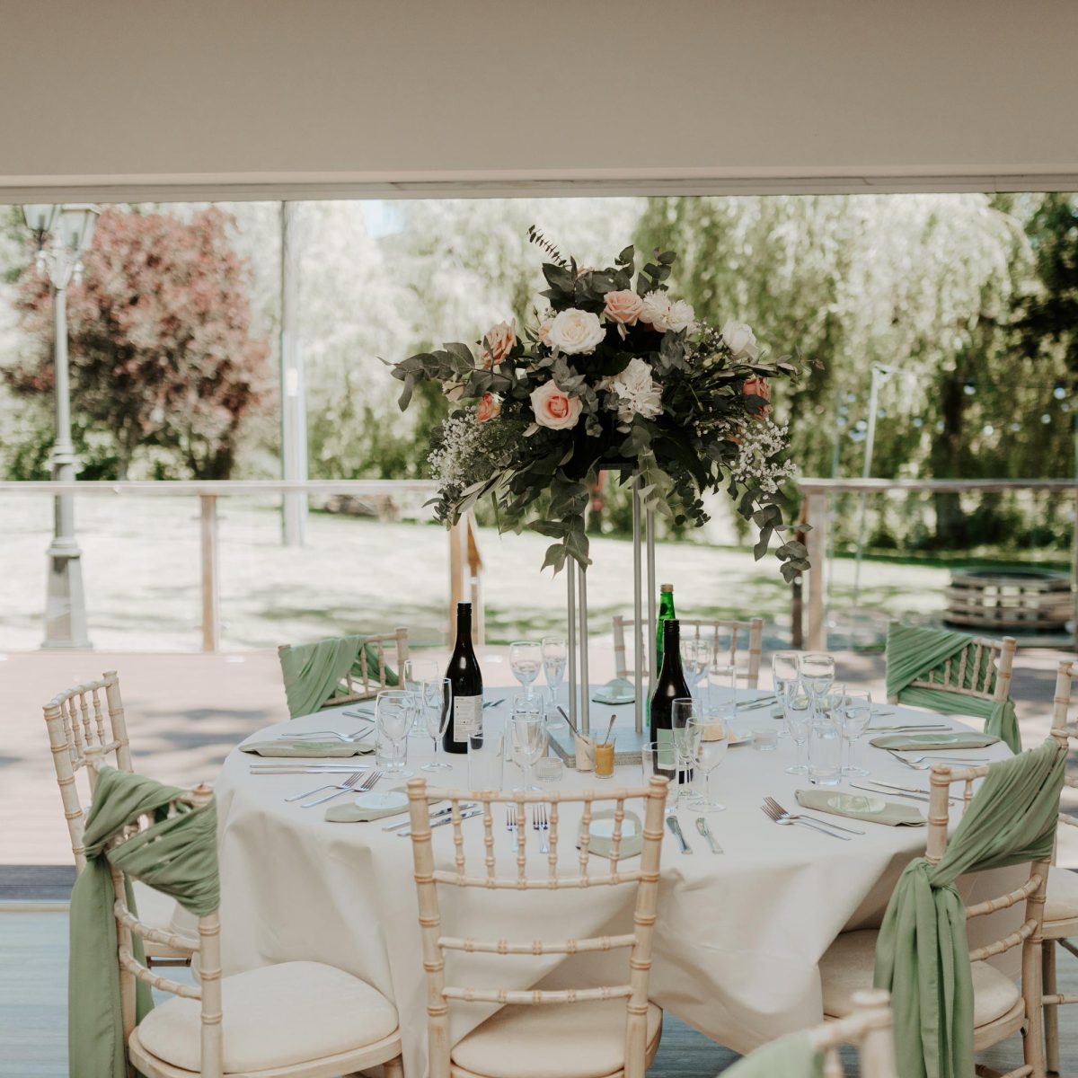 A table with a floral centrepiece and bottles of wine ready for a wedding reception at Wooladon Estate