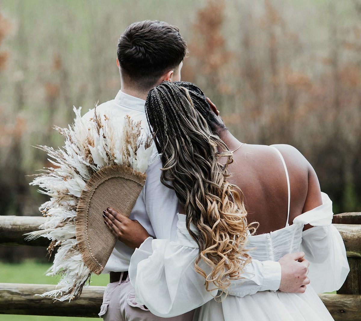 A bride and groom with their arms around each other standing by a fence on the land at Wooladon Estate