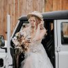 A bride stepping out of a Land Rover in front of the barn at Wooladon Estate