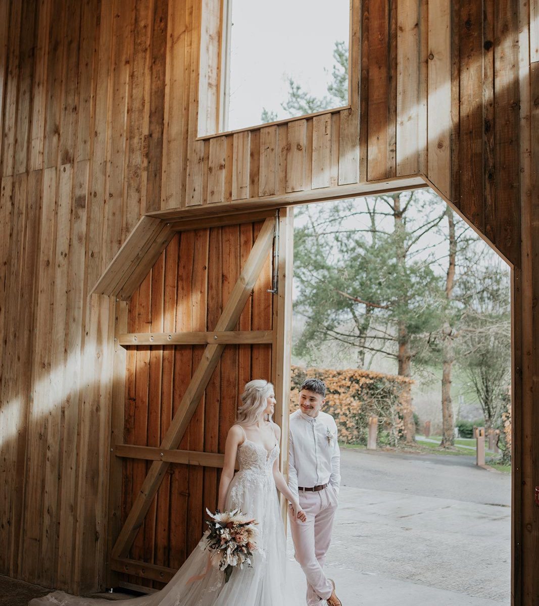 Newlyweds holding hands and leaning against the barn door at Wooladon Estate