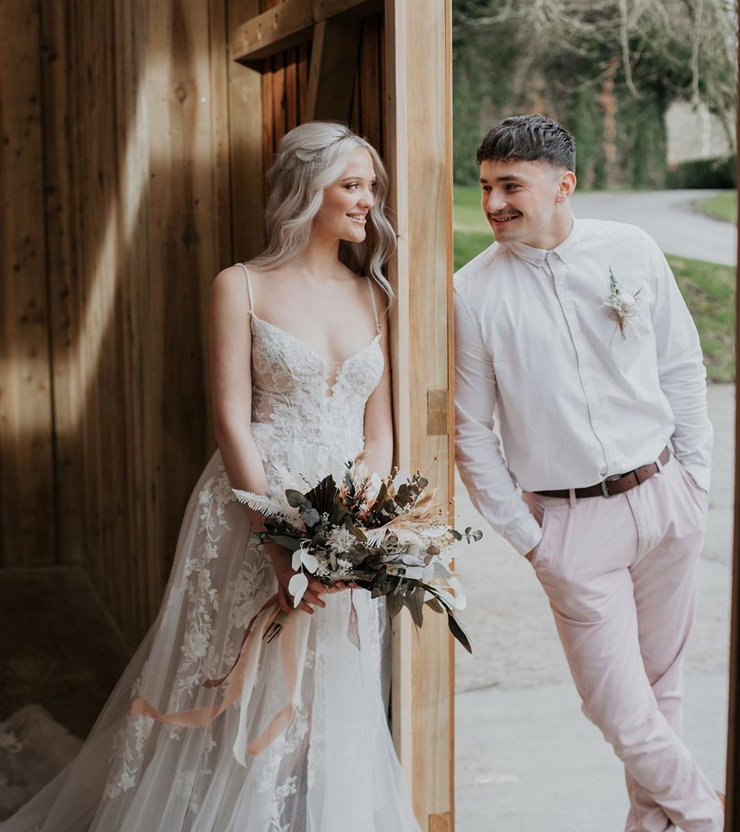 A bride and groom looking at each other as they lean on the door of the barn at Wooladon Estate