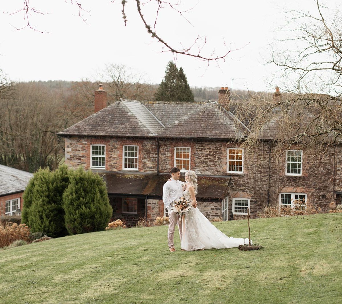 A young bride and groom standing on the lawn in front of the house at Wooladon Estate