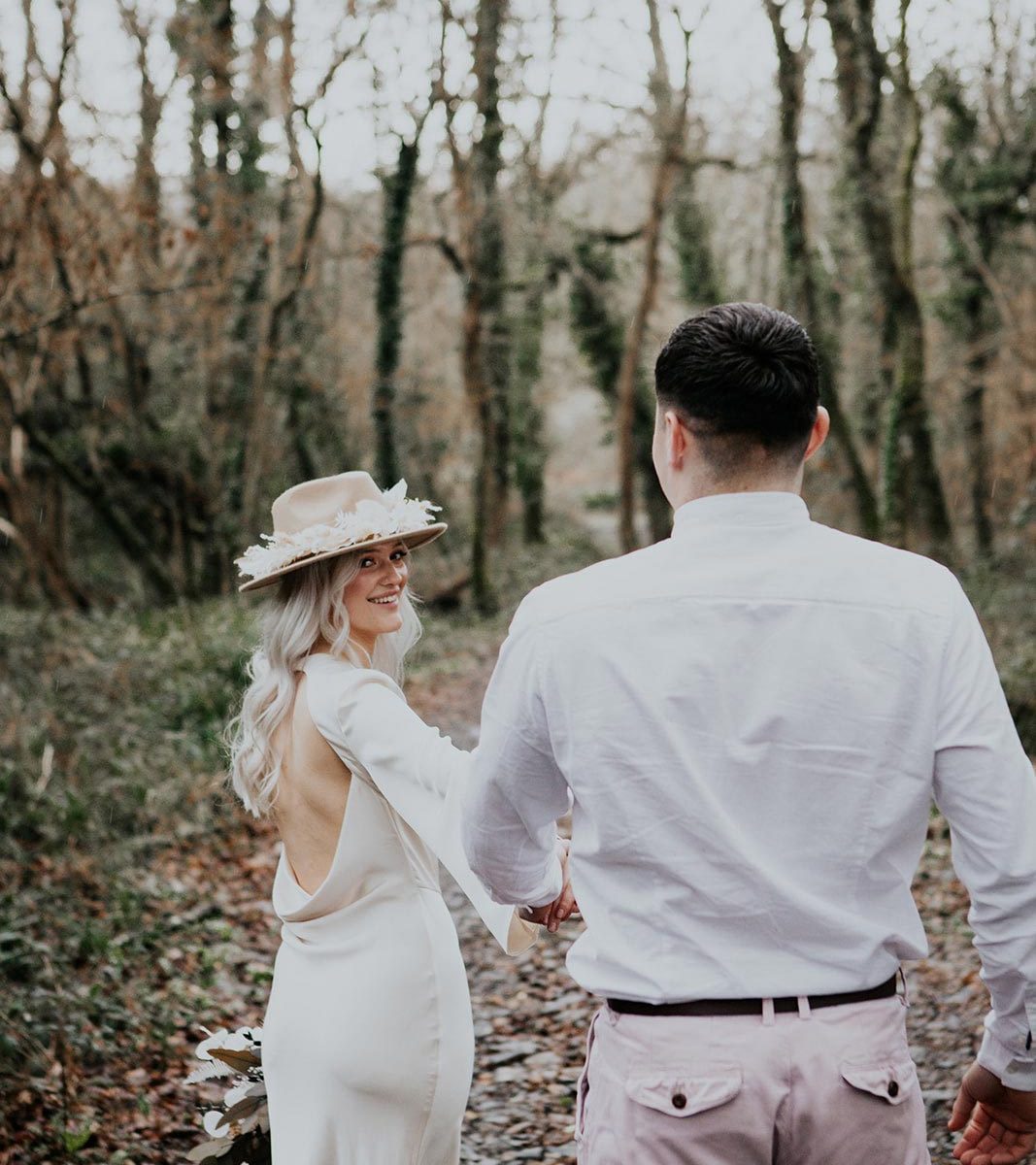 A newlywed bride and groom walking though the woodland at Wooladon Estate