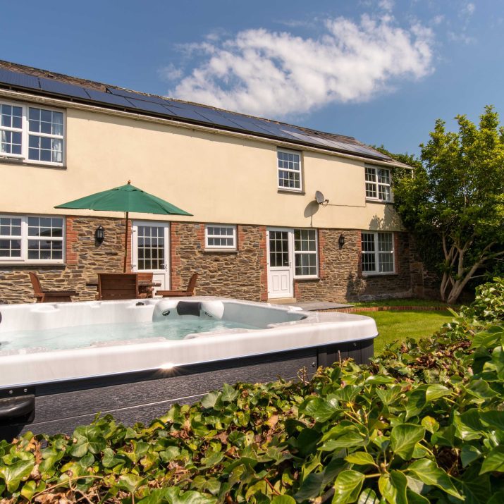 Barn cottage at Wooladon Estate external view with hot tub in garden and cottage in the background