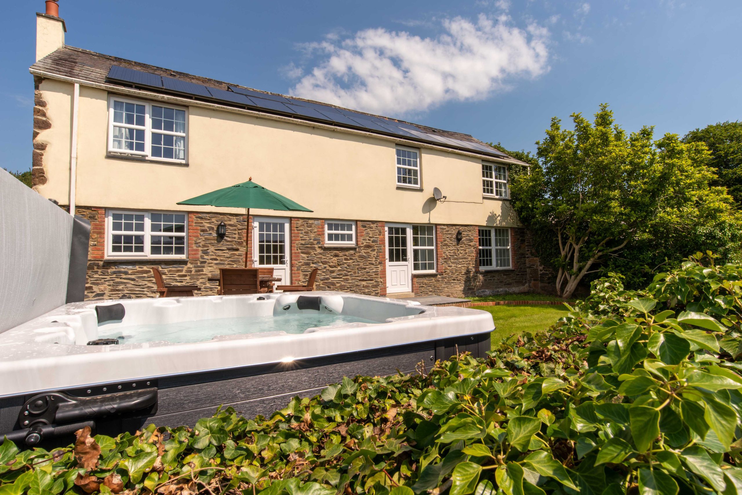 Barn cottage at Wooladon Estate external view with hot tub in garden and cottage in the background