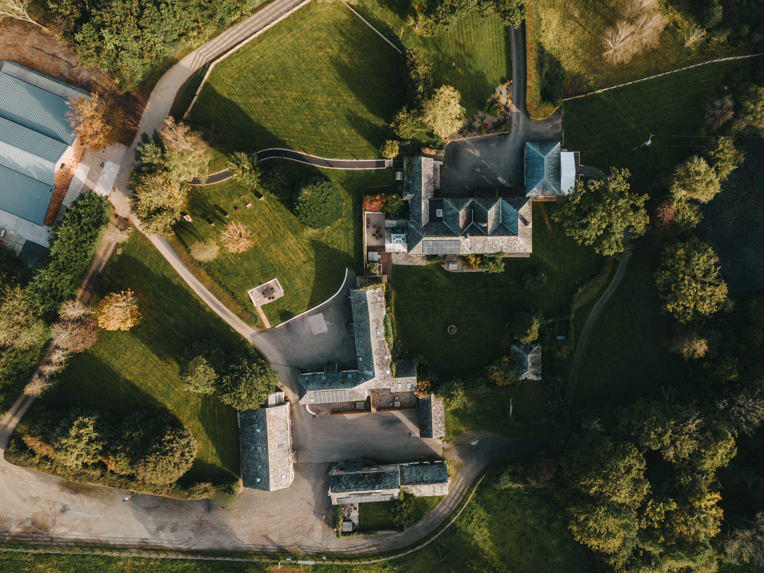 Birdseye view of Wooladon Estate showing the Main house, courtyard and neighboring cottages surrounded by green fields and woodland.