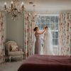 Bride stood by large window in the Bridal Suite at Wooladon Estate alongside her bridesmaid who fixes her veil.