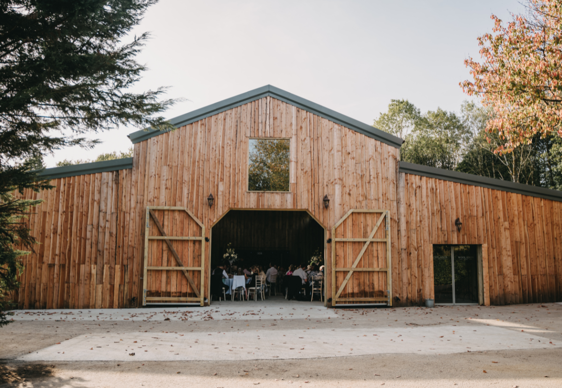 Devon wedding venue Wooladon Estate newly built barn with large barn doors wide open and tall ceilings.