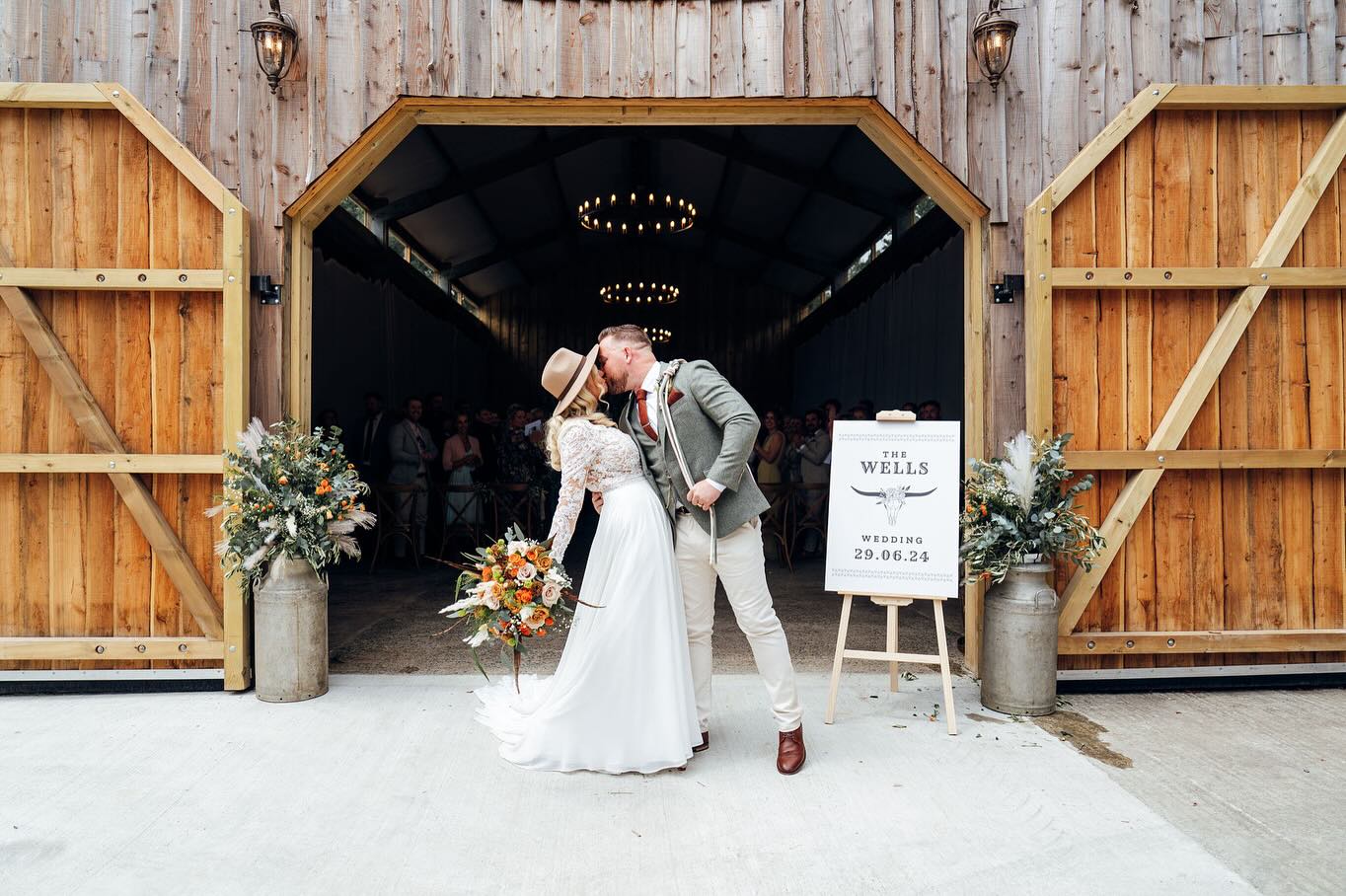 Newly married couple kissing in entrance of barn at a Rustic Wild West wedding at Wooladon Estate. Bride is wearing a cowboy hat.