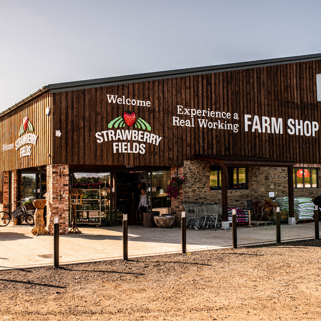 Strawberry Fields Farm Shop from view of shop entrance with large sign above the door and blue sky above.